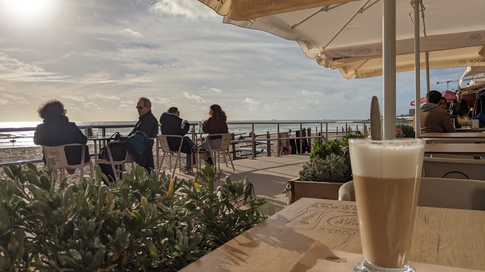 Seaside café in Lisbon with a galão on the table
